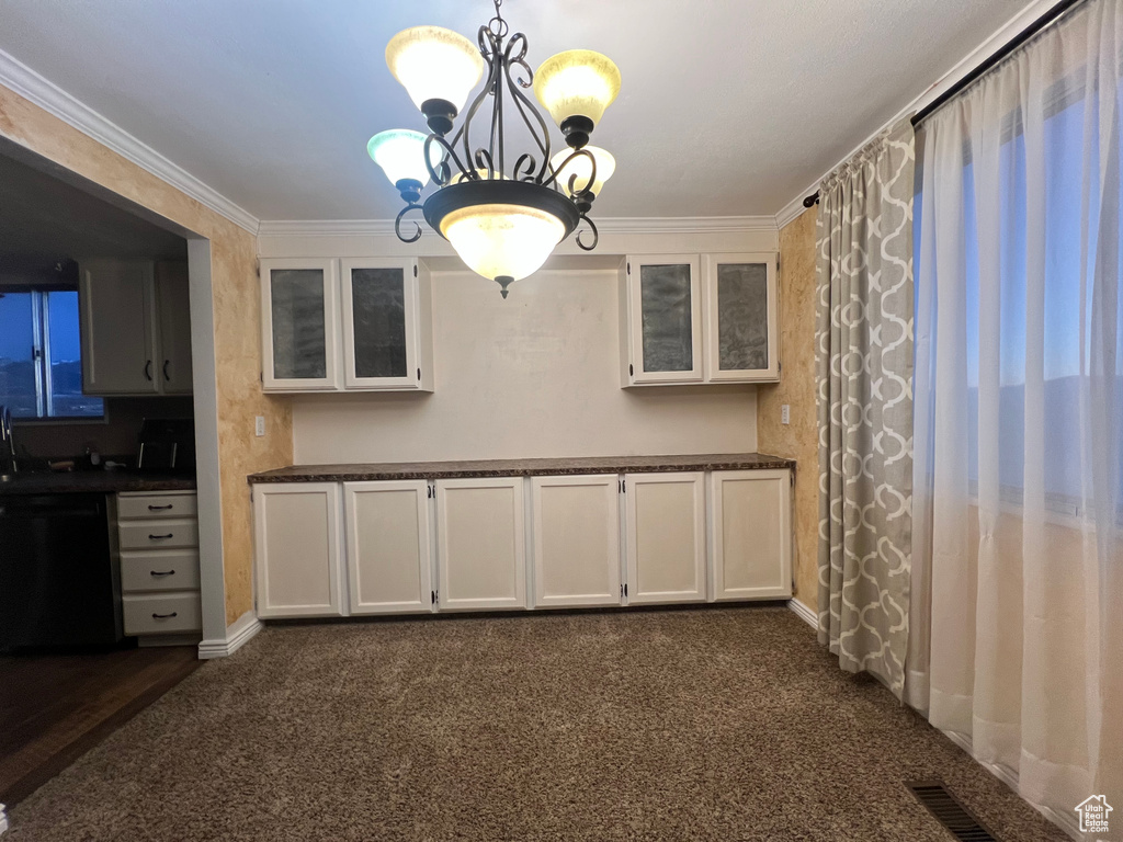 Unfurnished dining area with visible vents, dark carpet, a notable chandelier, and ornamental molding