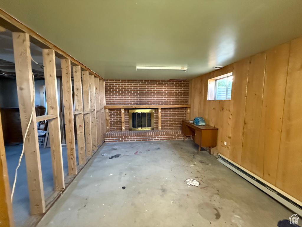 Below grade area featuring a baseboard heating unit, a fireplace, and wood walls