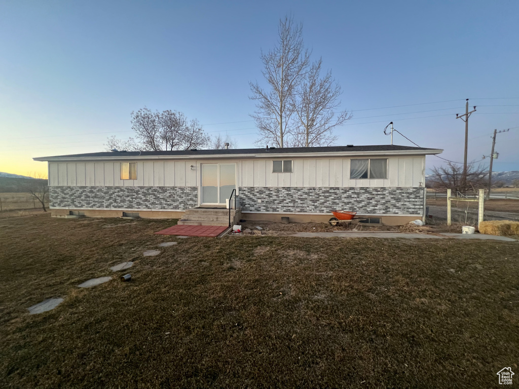 View of front of property featuring board and batten siding, entry steps, and a front lawn