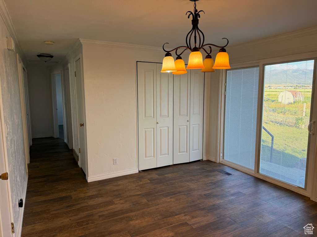 Unfurnished dining area featuring a chandelier, dark wood-style flooring, ornamental molding, and baseboards