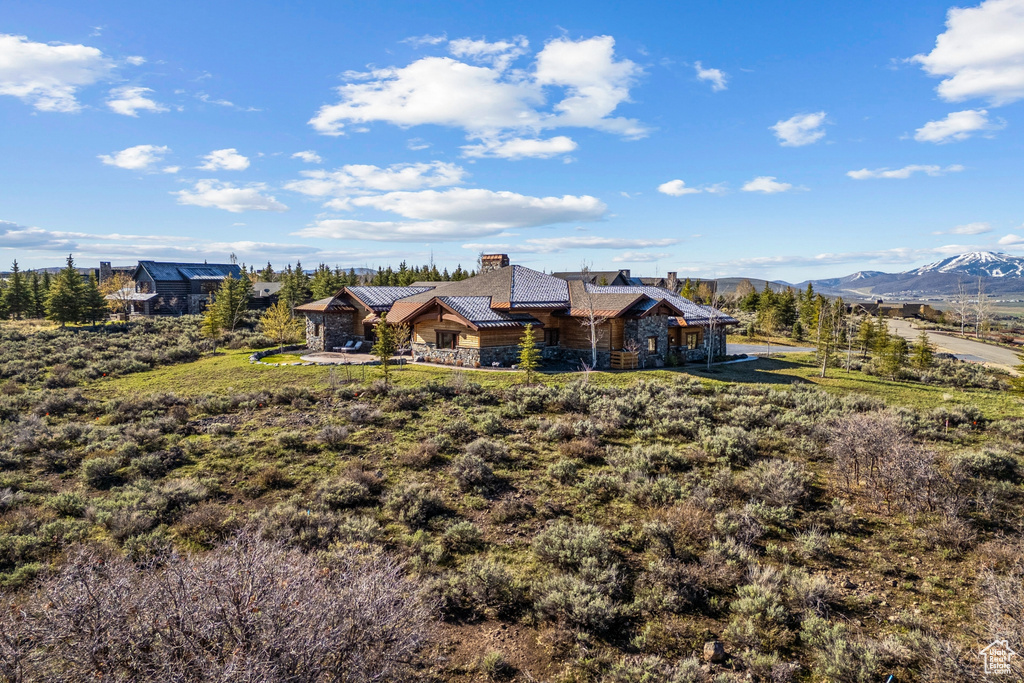 Back of property with a standing seam roof, a mountain view, a chimney, and stone siding