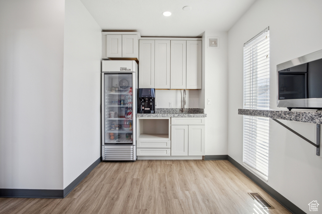 Kitchen featuring beverage cooler, visible vents, light wood finished floors, and baseboards