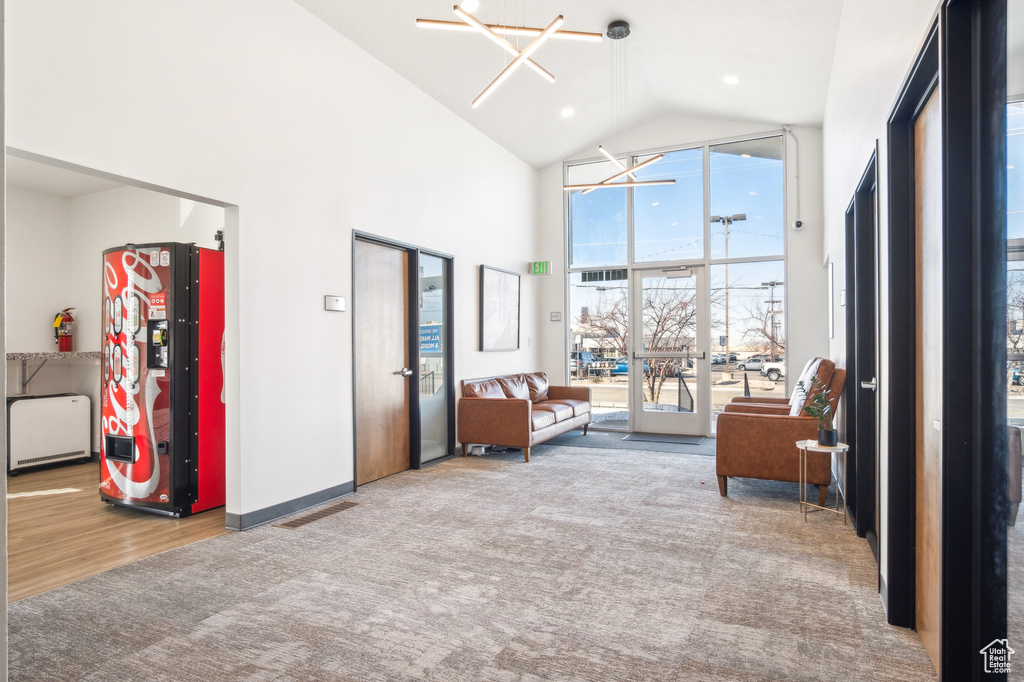 Living room featuring visible vents, baseboards, carpet floors, an inviting chandelier, and high vaulted ceiling
