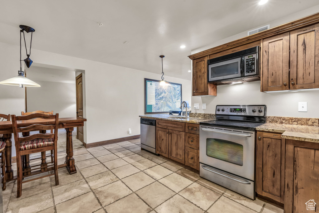 Kitchen featuring stainless steel appliances, decorative light fixtures, recessed lighting, and light stone counters