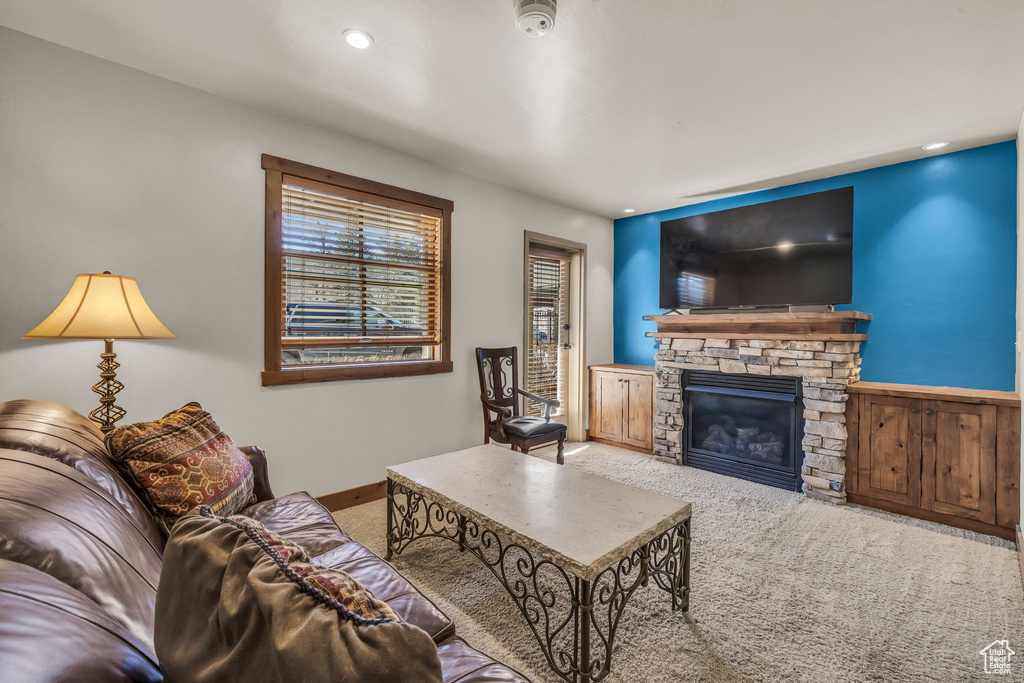 Living room featuring carpet floors, a stone fireplace, and recessed lighting