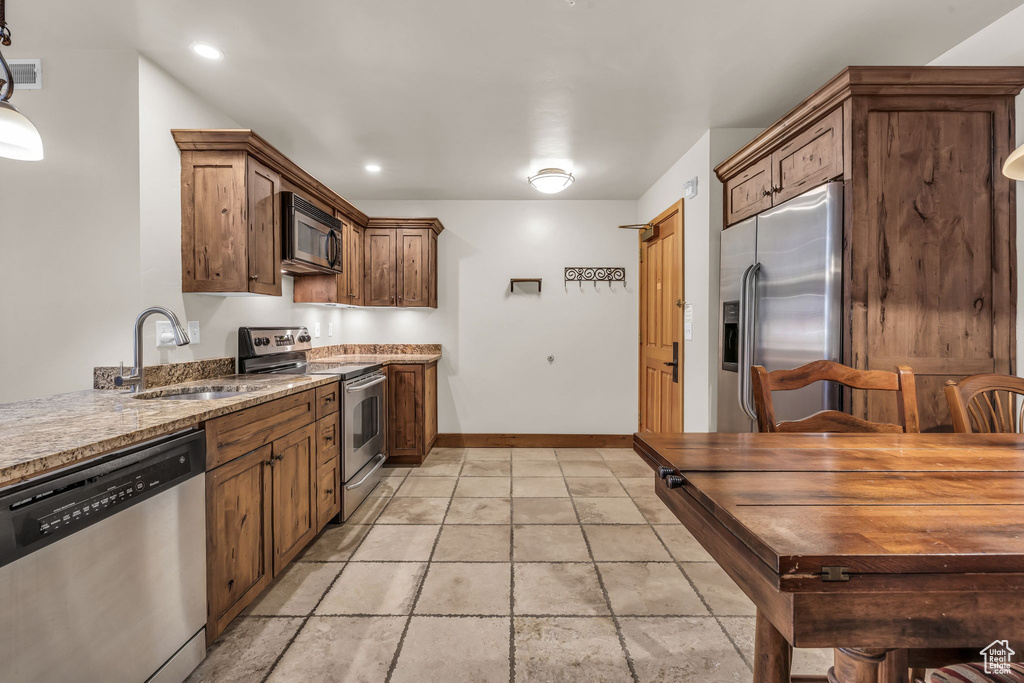 Kitchen featuring appliances with stainless steel finishes, light stone counters, and recessed lighting