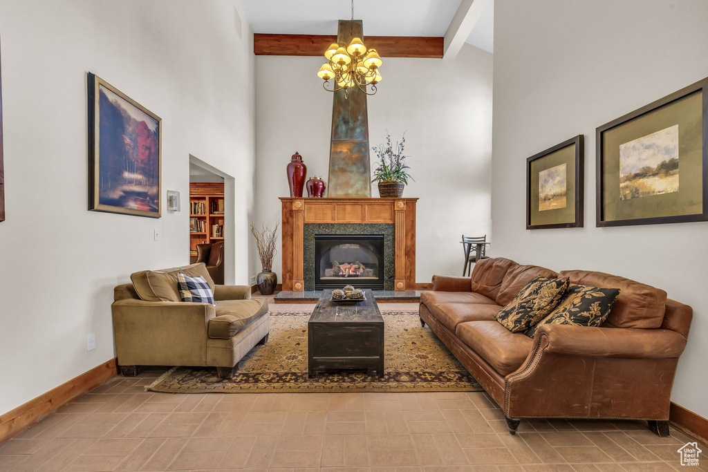 Living room featuring beam ceiling, a chandelier, a towering ceiling, and a premium fireplace