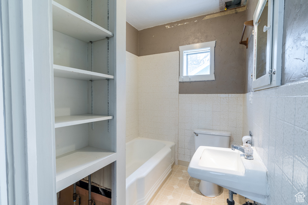 Bathroom featuring sink, tile walls, a washtub, toilet, and tile patterned floors