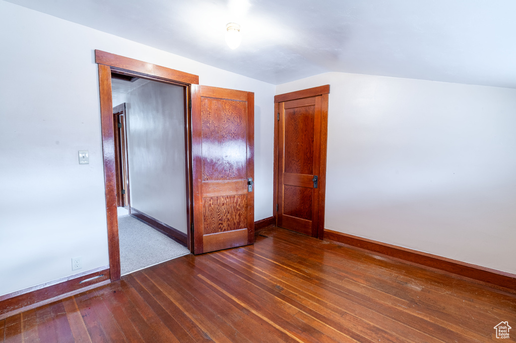 Unfurnished bedroom featuring dark hardwood / wood-style flooring, vaulted ceiling, and a closet