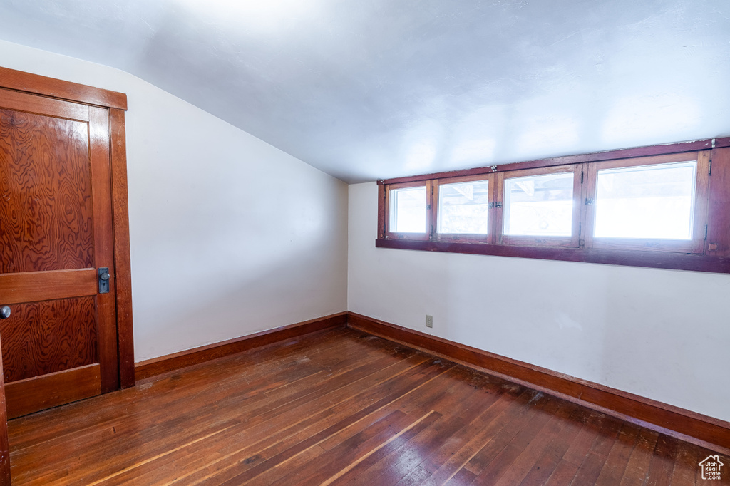 Empty room featuring lofted ceiling and dark hardwood / wood-style flooring