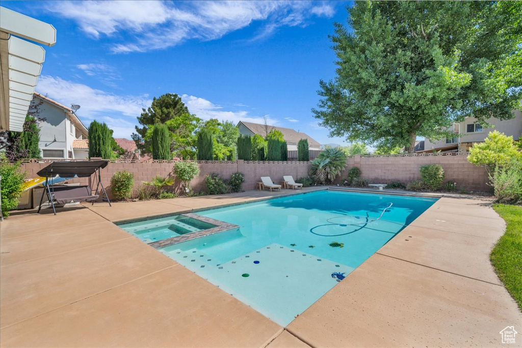 View of swimming pool with a fenced backyard, a patio area, and a pool with connected hot tub