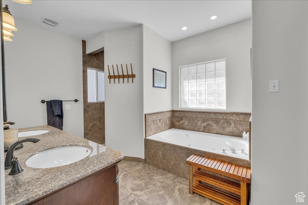 Full bath featuring a jetted tub, double vanity, and recessed lighting