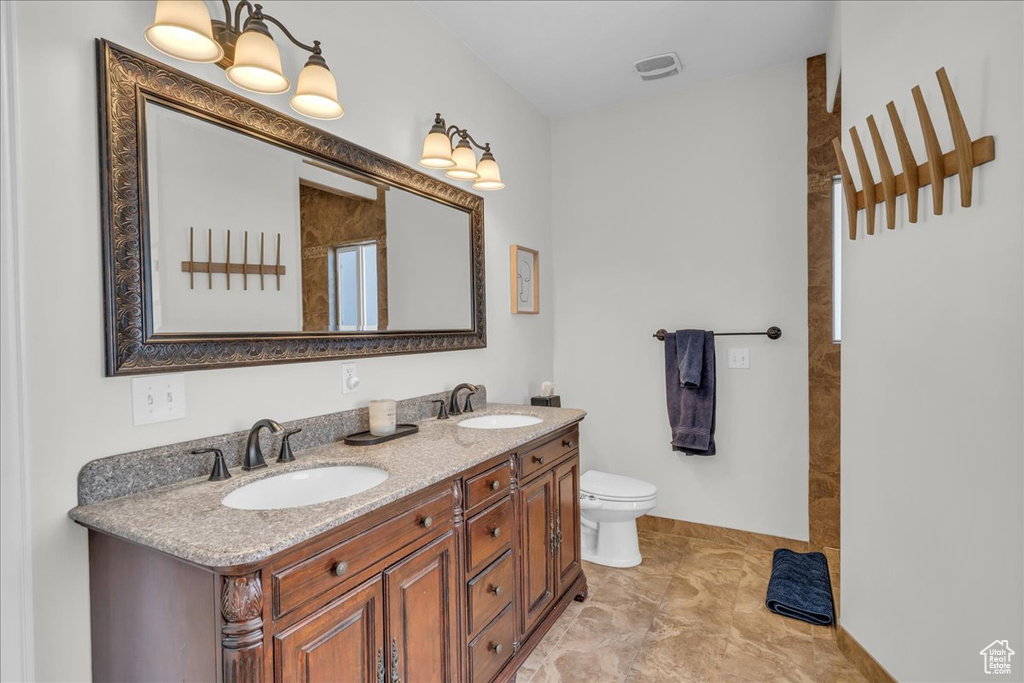 Full bath with double vanity, toilet, and a shower
