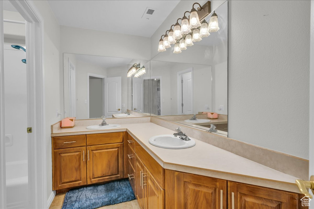 Full bath with vanity, a chandelier, and tile patterned flooring