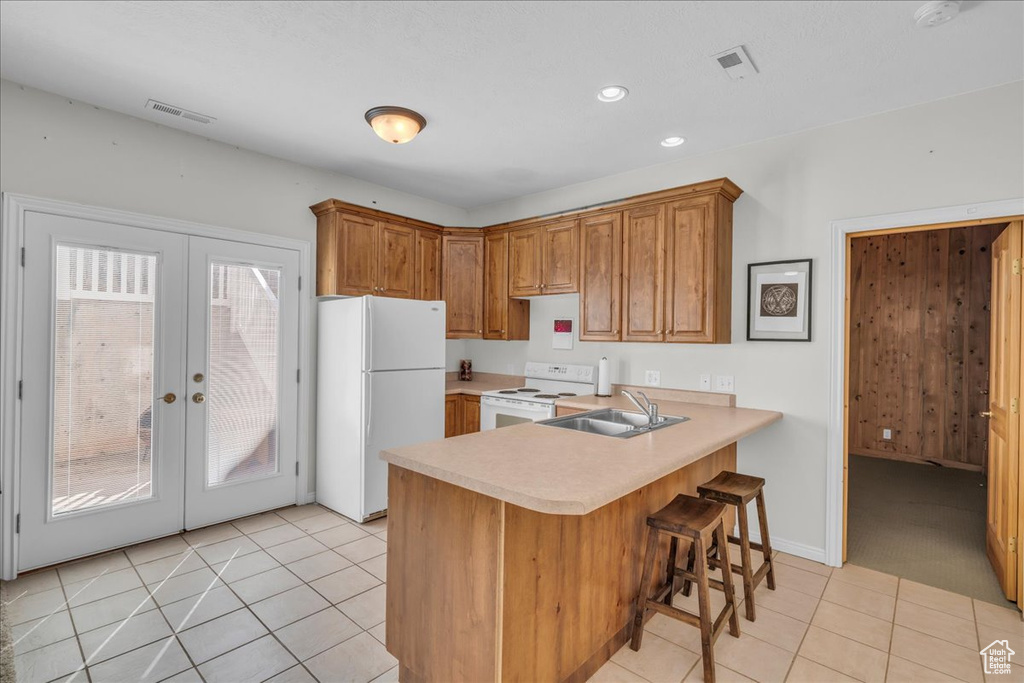 Kitchen with white appliances, a sink, french doors, light countertops, and a peninsula