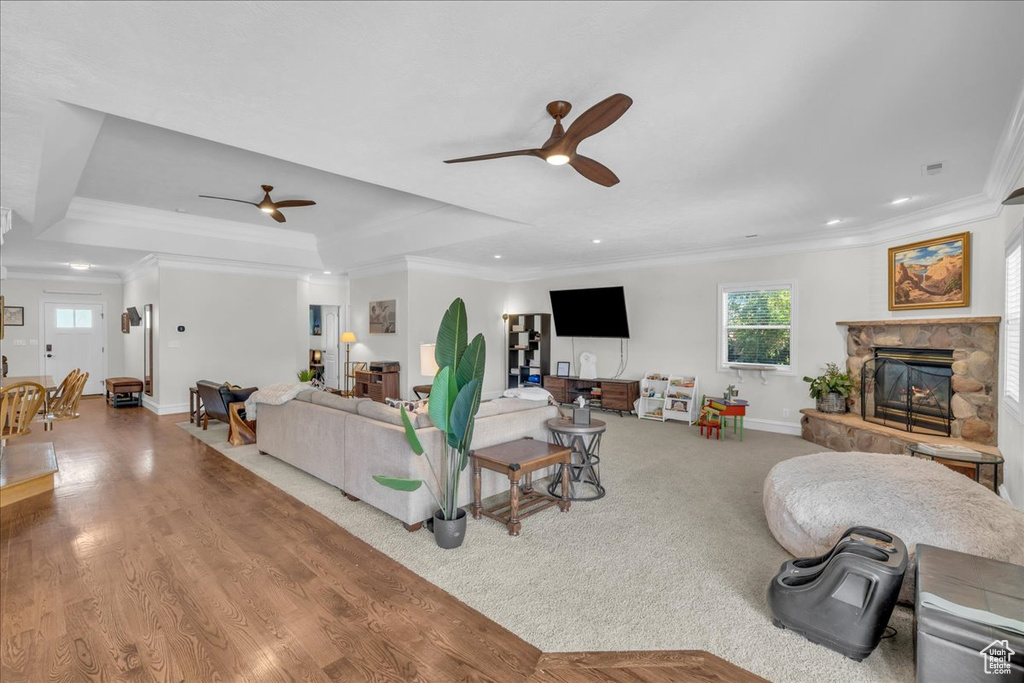 Living room featuring a ceiling fan, crown molding, a stone fireplace, healthy amount of natural light, and recessed lighting