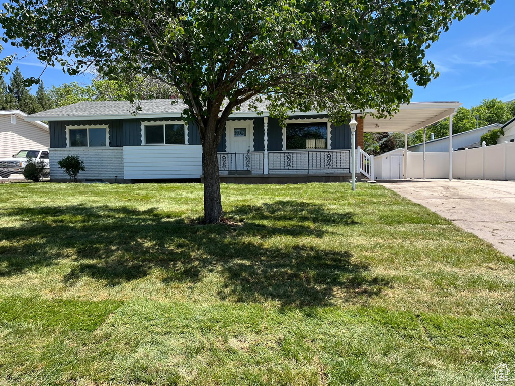 View of front of house with board and batten siding, a carport, covered porch, driveway, and brick siding
