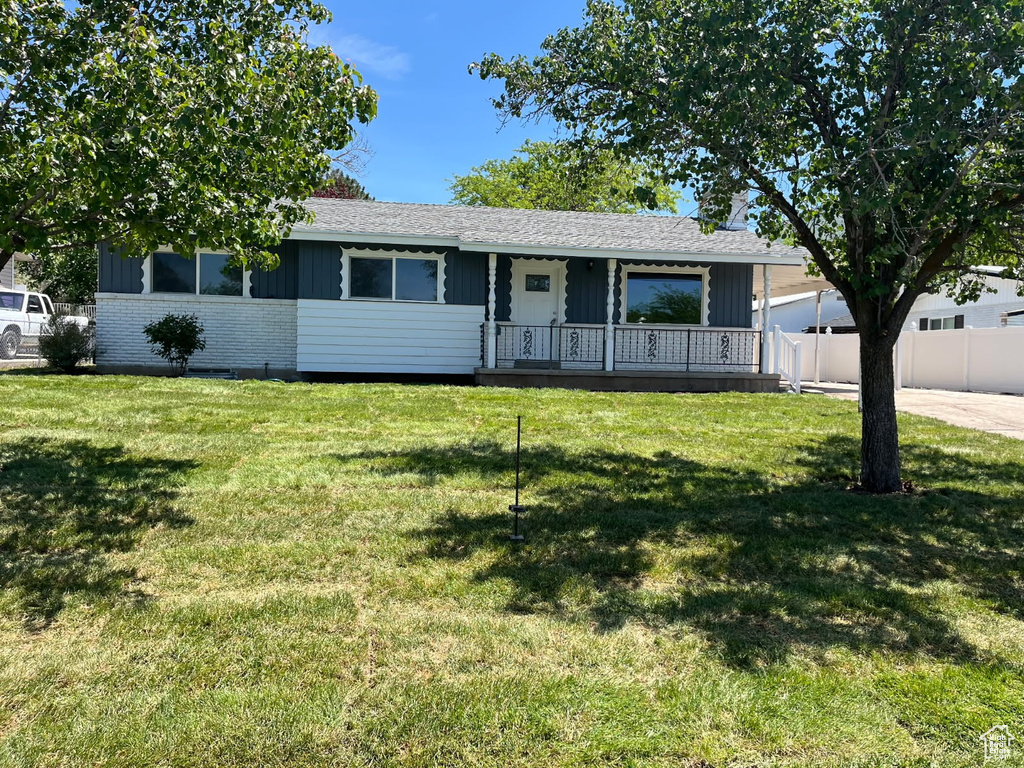 Single story home with board and batten siding, covered porch, and roof with shingles