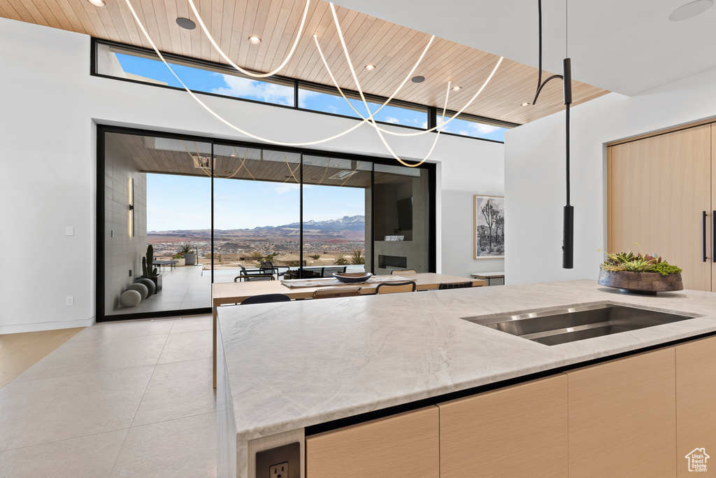 Kitchen featuring light brown cabinets, a mountain view, wood ceiling, light stone countertops, and pendant lighting