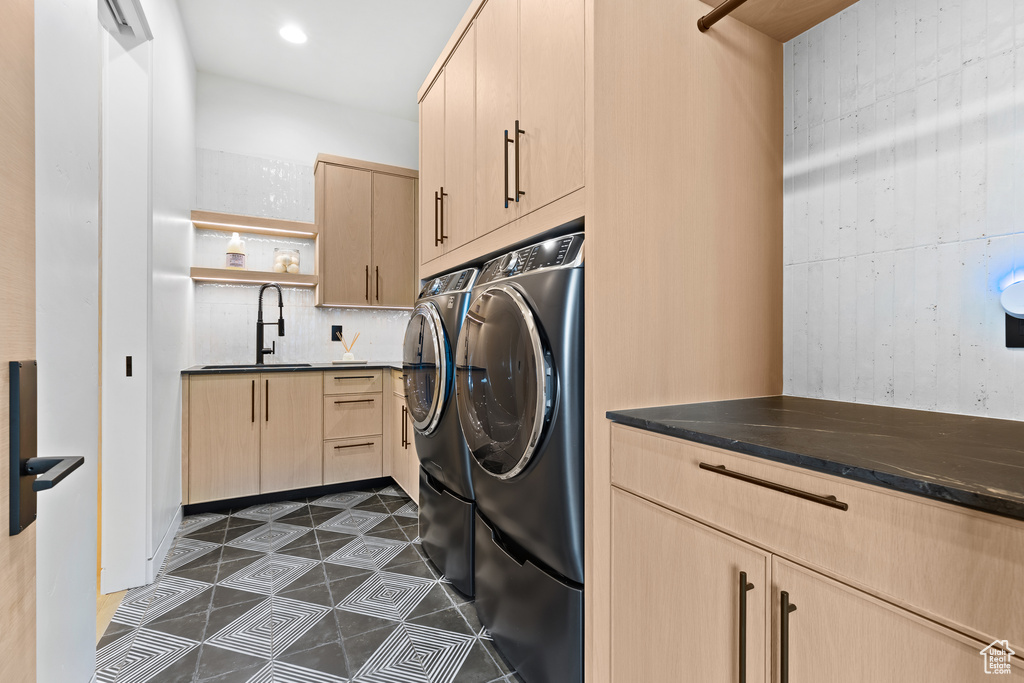 Laundry area with cabinet space, washing machine and dryer, dark tile patterned floors, a sink, and recessed lighting