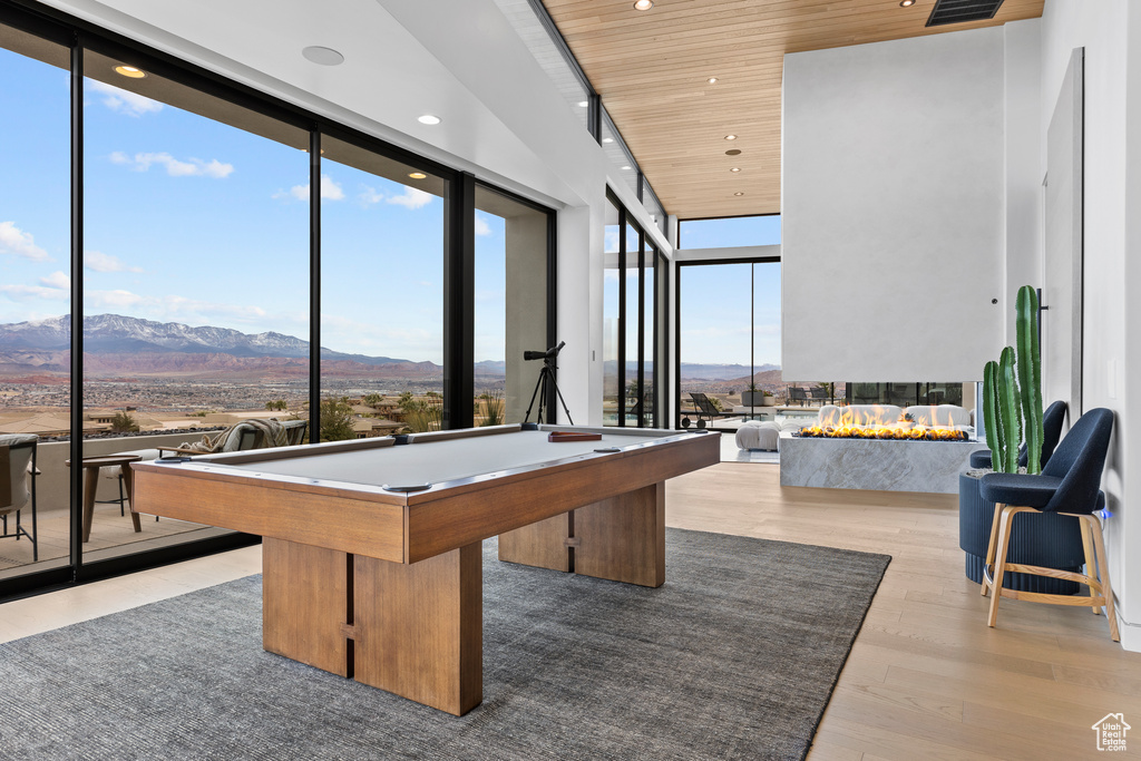 Recreation room with wood ceiling, a wall of windows, wood finished floors, and a mountain view