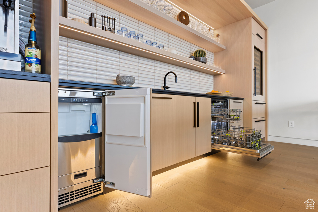 Kitchen featuring light wood-style floors, dark countertops, a sink, and open shelves