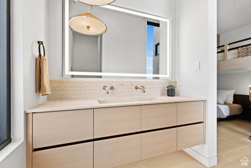 Ensuite bathroom with vanity, ensuite bath, and wood finished floors