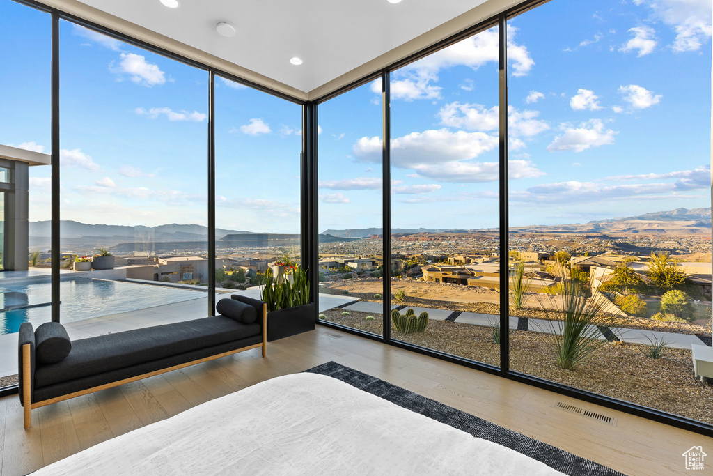 Unfurnished bedroom featuring visible vents, expansive windows, a mountain view, and wood finished floors