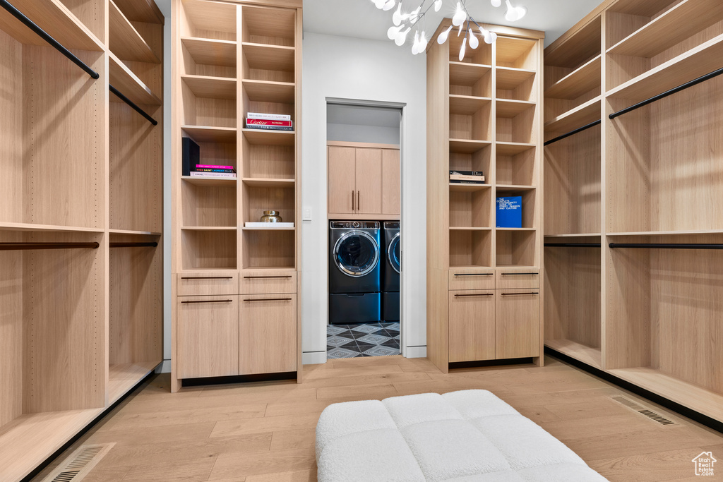 Walk in closet with an inviting chandelier, light wood-style flooring, visible vents, and washer and clothes dryer