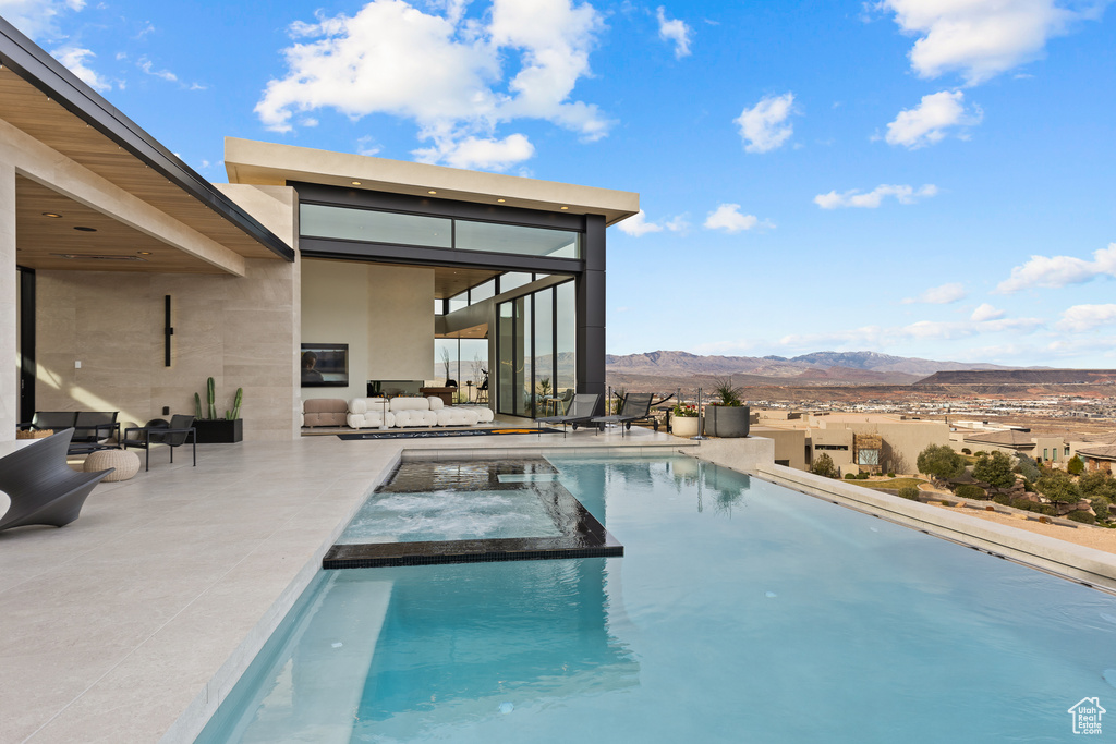 View of pool with a patio area, a pool with connected hot tub, and a mountain view