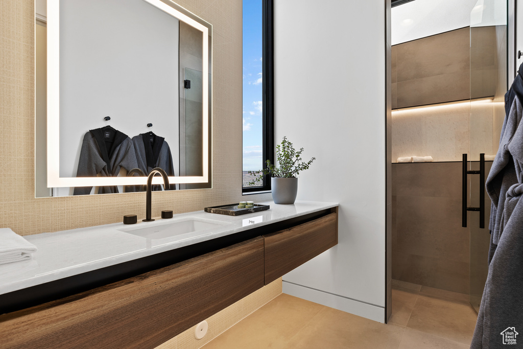 Bathroom with tiled shower, tile patterned flooring, and vanity