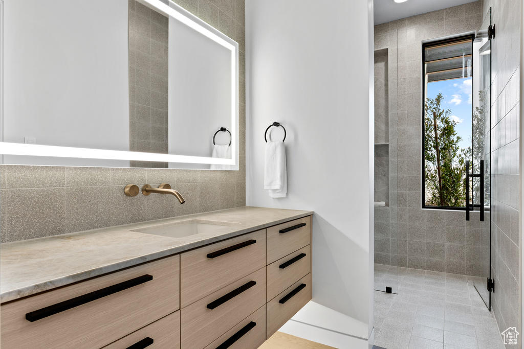 Full bath featuring plenty of natural light, tasteful backsplash, a tile shower, and vanity