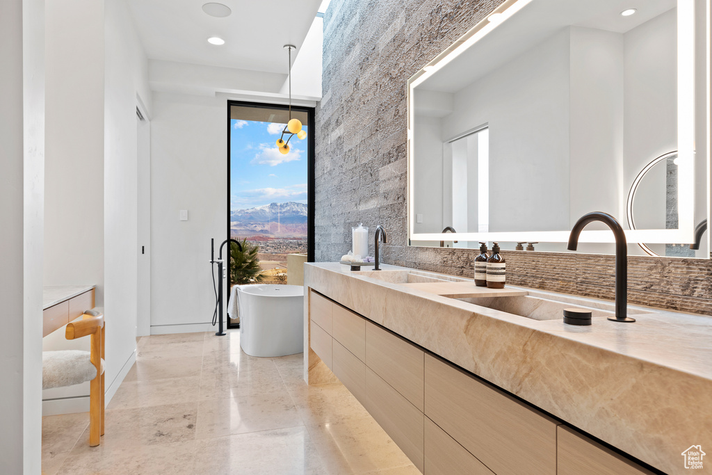 Bathroom featuring marble finish floor, floor to ceiling windows, recessed lighting, a freestanding bath, and vanity