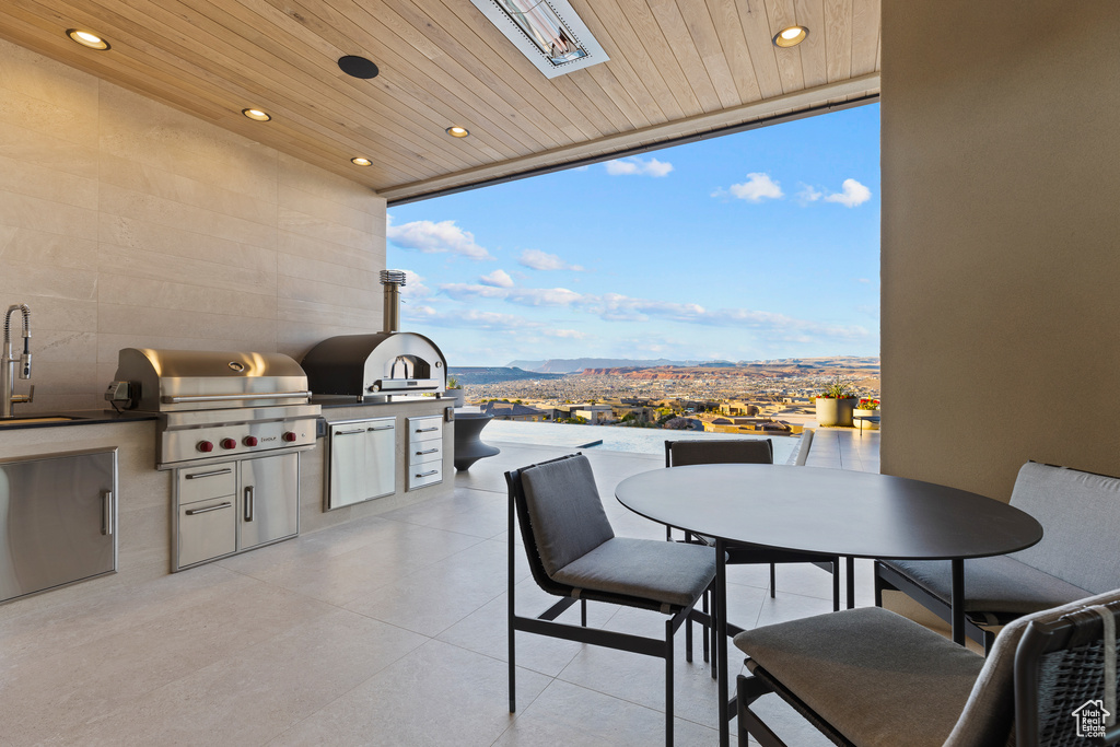 View of patio with exterior kitchen, outdoor dining area, a sink, and a grill