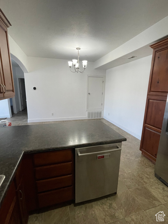 Kitchen featuring visible vents, arched walkways, dark countertops, a peninsula, and stainless steel dishwasher