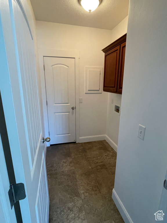 Laundry room featuring cabinet space, baseboards, and a textured ceiling