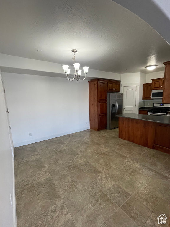 Kitchen featuring dark countertops, an inviting chandelier, appliances with stainless steel finishes, and open floor plan