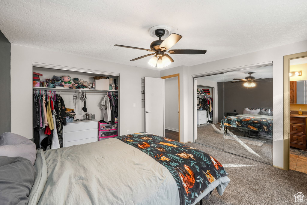 Bedroom featuring multiple closets, ceiling fan, a textured ceiling, and carpet flooring