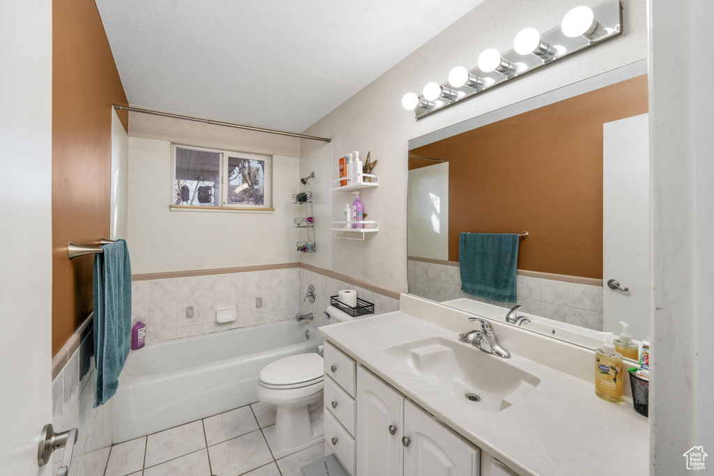 Full bathroom with toilet, tile walls, vanity, tile patterned floors, and a bathtub