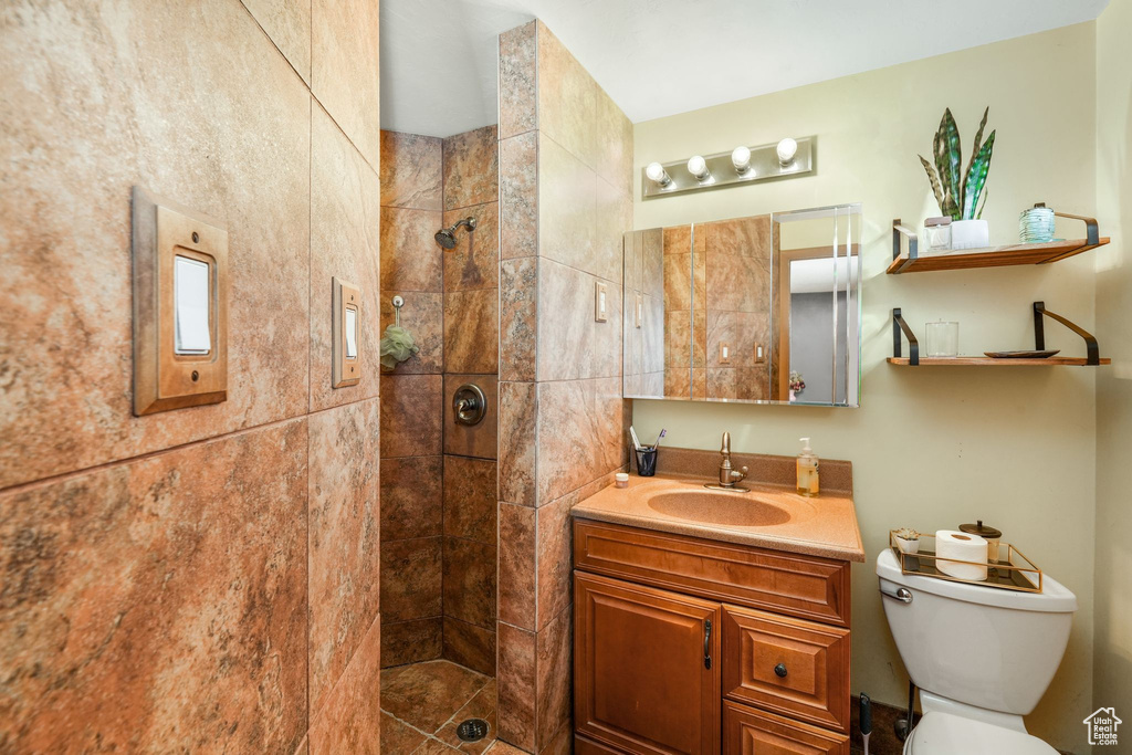 Bathroom featuring toilet, a tile shower, and vanity
