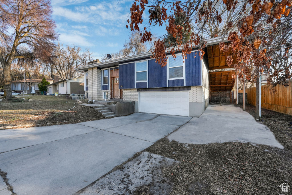 View of front of property with an attached garage, fence, concrete driveway, and brick siding