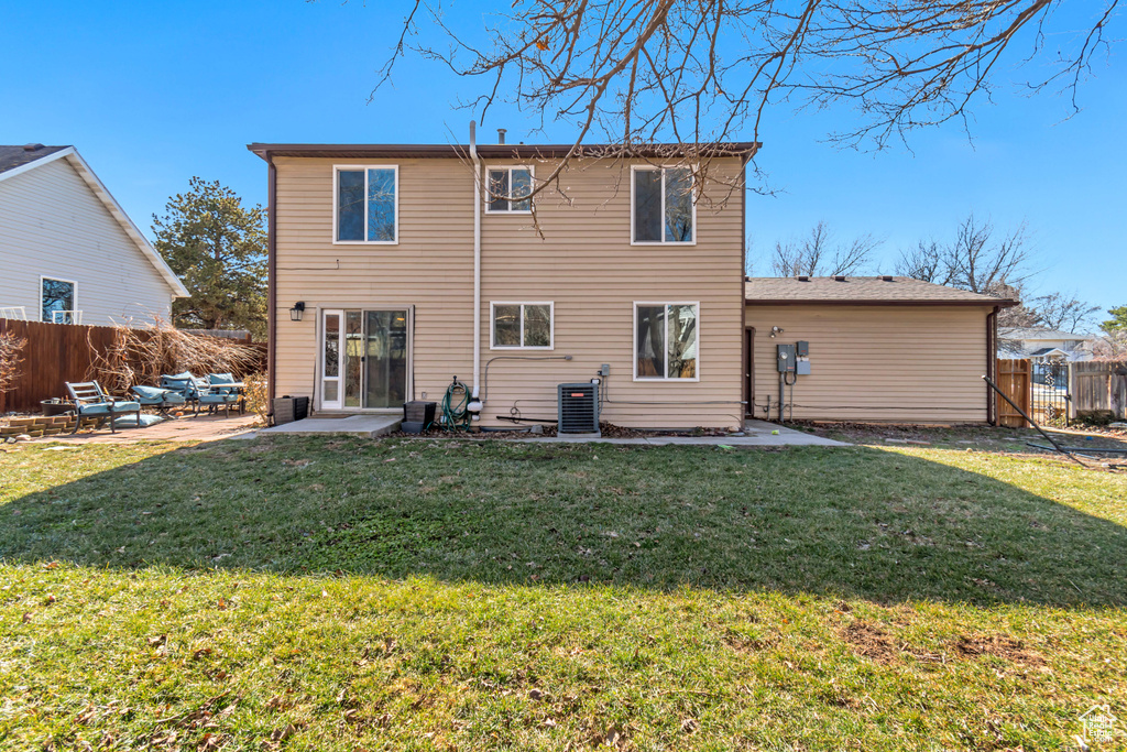 Back of house featuring a patio area, a fenced backyard, central AC unit, and a lawn