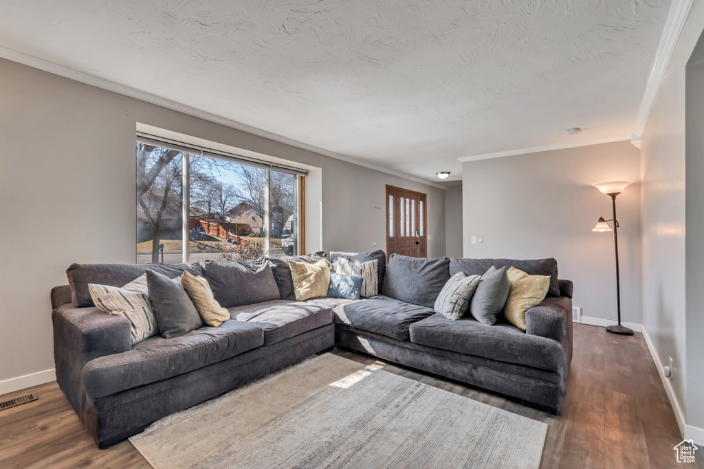 Living room with visible vents, crown molding, baseboards, and wood finished floors