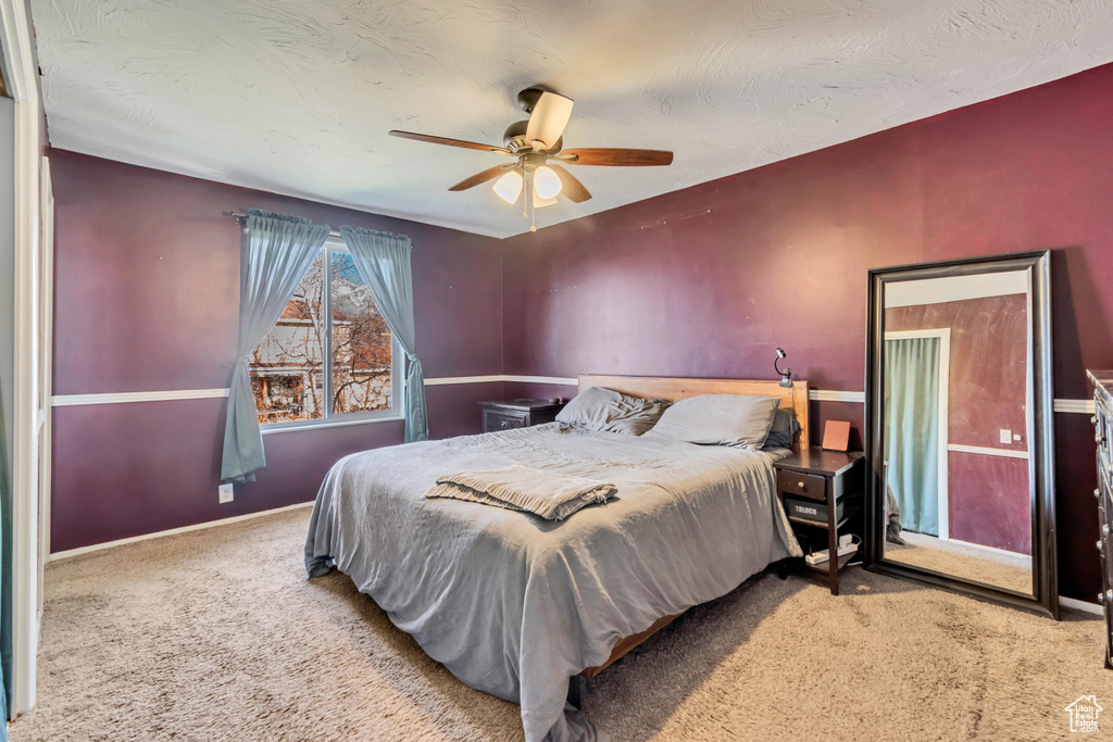 Carpeted bedroom featuring a textured ceiling and a ceiling fan