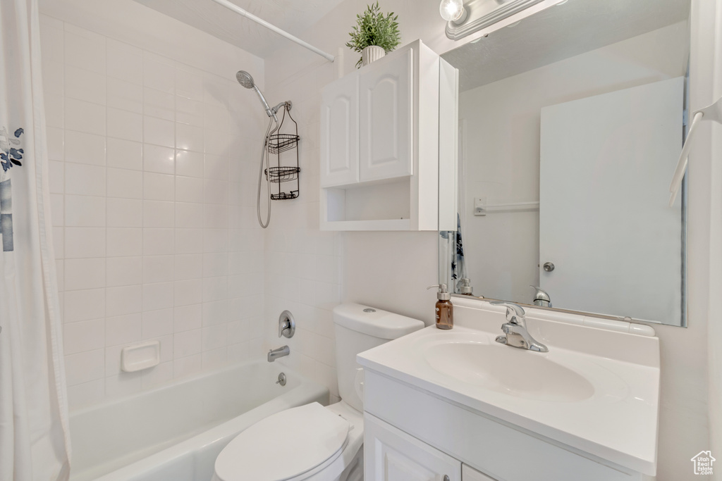 Bathroom with toilet, shower / tub combo with curtain, and vanity