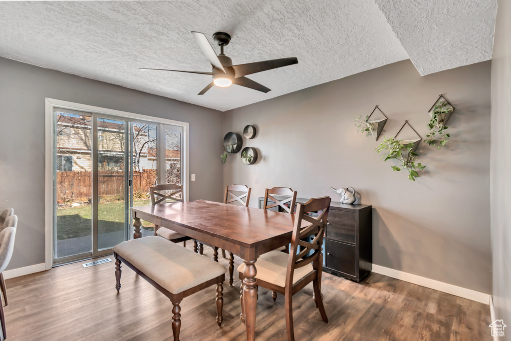 Dining room with visible vents, a textured ceiling, baseboards, and wood finished floors