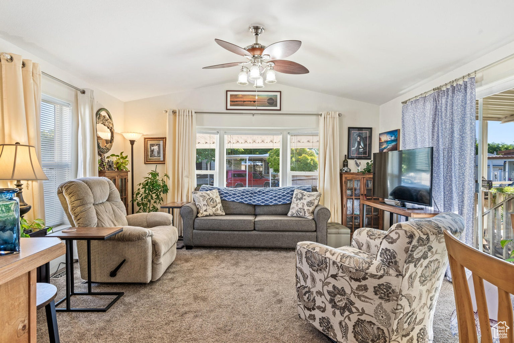 Living room featuring a ceiling fan, lofted ceiling, and carpet flooring
