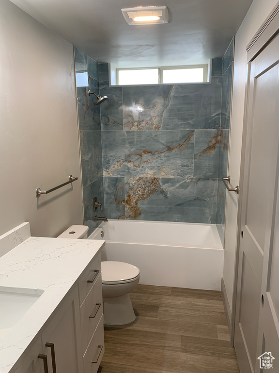Bathroom with toilet, shower / bath combination, wood finished floors, and vanity