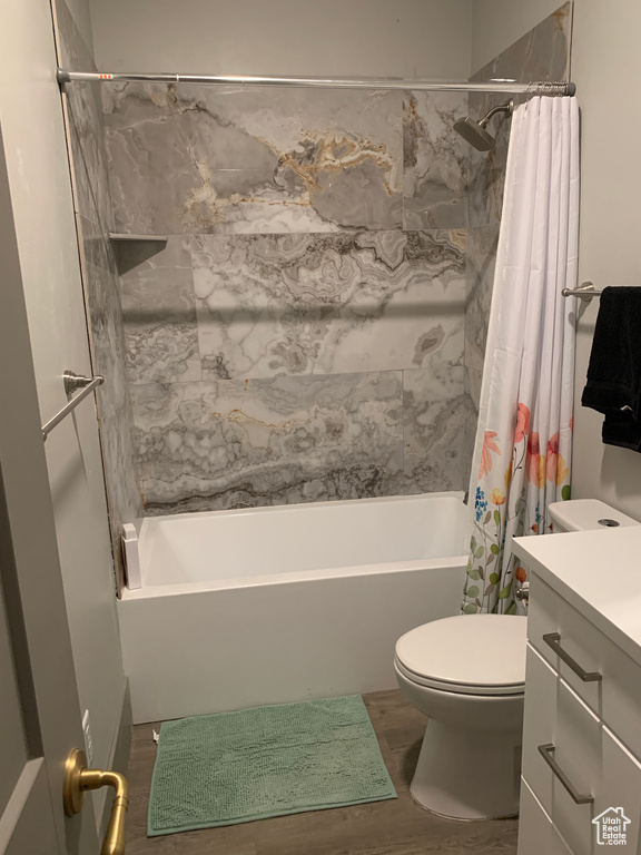 Full bathroom with shower / bath combination with curtain, vanity, toilet, and wood finished floors