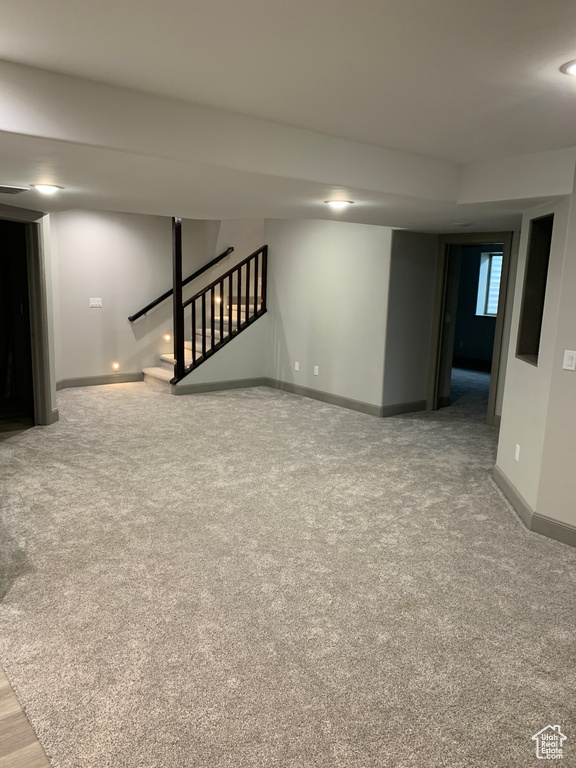 Basement with carpet floors, visible vents, stairway, and baseboards